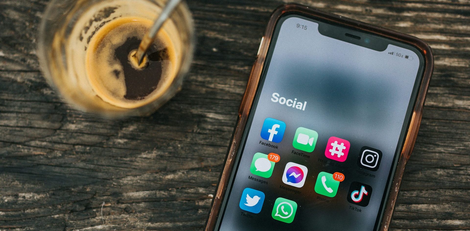 A smartphone with social media icons sits on a table next to a cup of coffee. Publishers have seen success with WhatsApp channels and communities to drive traffic to their properties, and we see an opportunity to use that success to drive app downloads. Photo by Nathan Dumlao on Unsplash